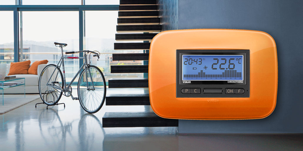 From vision to the final product. Vimar Arke developed by quickpartners, specialized in Design concept, product design, design guidelines, 3D-CAD design, pre-engineering, innovation management, product graphics and interface design for technical consumer goods. Performative Chrono thermostat with orange bimaterial decorative frame in modern house with bicycle.