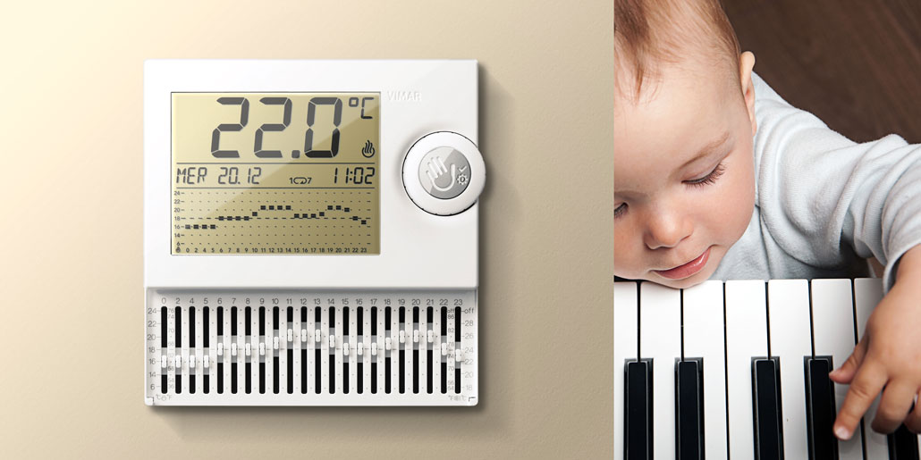 Vimar thermostat with mechanical levers for simplified programming and large LCD display for maximum readability with push wheel user interaction design by quickpartners+ in open state with piano playing child