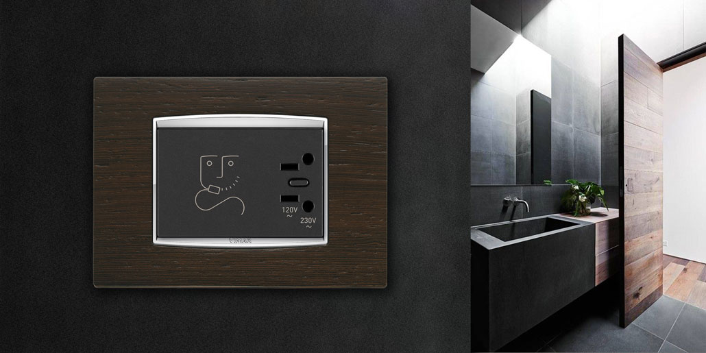 Vimar Eikon top level switch range design quickpartners with more than 150 modular functions and 100 design plates with precious materials like wood, metal, glass and stone. Razor socket in wooden plate and crome element in elegant modern bathroom and wooden door